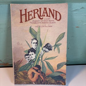 May include: A vintage book cover for "Herland: A Lost Feminist Utopian Novel" by Charlotte Perkins Gilman. The cover features a collage of faces, a seated figure, and green foliage against a sunset backdrop. The title is in a bold, maroon font.