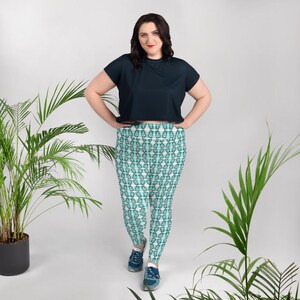 May include: A woman wearing a black cropped top and teal and white patterned leggings. The leggings have a geometric design with a repeating pattern of teal and white squares.