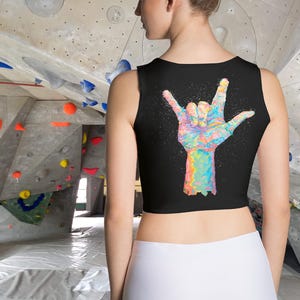 Op de afbeelding: Zwart, mouwloos crop top met een kleurrijke handgeschilderde afbeelding van een hand die het 'ik hou van je' gebarentaalgebaar maakt.