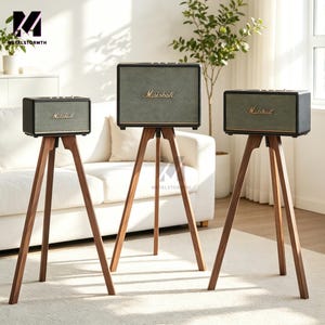 Può includere: Tre altoparlanti Marshall su supporti a treppiede in legno. Gli altoparlanti hanno una cornice nera e una parte anteriore in rete verde con il logo Marshall in oro. I supporti sono in legno scuro.