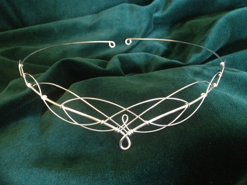Puede incluir: Diadema de alambre plateado con un dise&ntilde;o delicado e entrelazado. La diadema est&aacute; adornada con peque&ntilde;as cuentas redondas.