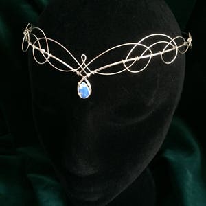 Op de afbeelding: Zilveren draad hoofdband met een blauwe traanvormige edelsteen hanger.