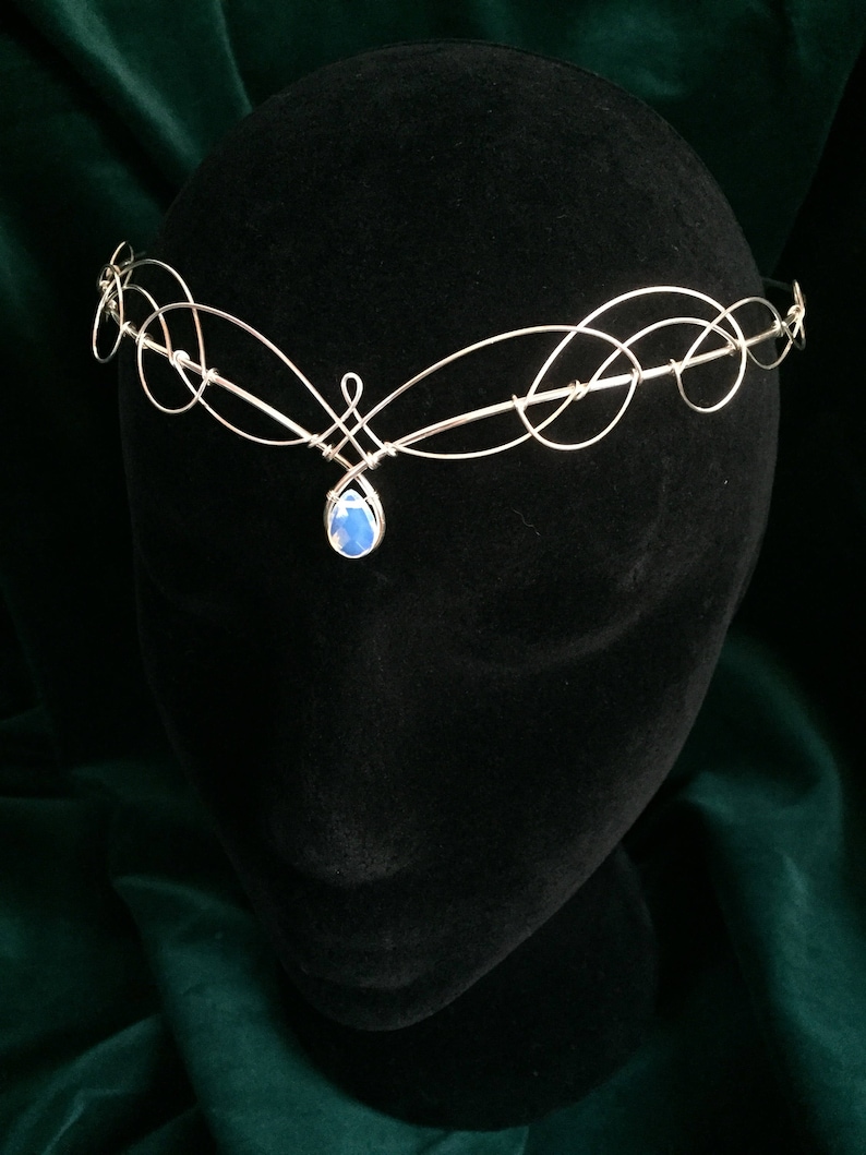 Op de afbeelding: Zilveren draad hoofdband met een blauwe traanvormige edelsteen hanger.