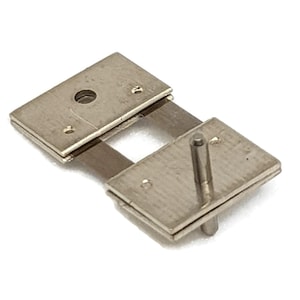 May include: A silver metal watch band link with a pin and two plates. The plates have small holes on the sides.