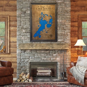 May include: A rustic living room with a stone fireplace and a framed map of a lake. The map is titled "The Solberg Family Lake House" and features a blue lake with islands. Two leather armchairs are positioned in front of the fireplace.
