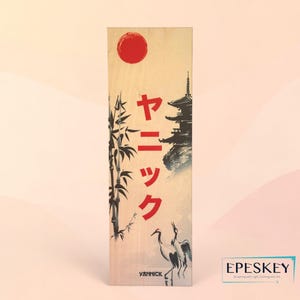 Puede incluir: Panel rectangular de madera con un diseño de inspiración japonesa. La obra de arte incluye un sol rojo, tallos de bambú, una pagoda y dos grullas. Se muestran caracteres japoneses rojos. El panel tiene el texto "YANNICK" en la parte inferior.