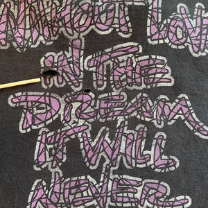 K&ouml;nnte beinhalten: Ein schwarzes T-Shirt mit einer lilafarbenen Grafik, auf der "Without love in the dream it will never come true" steht.