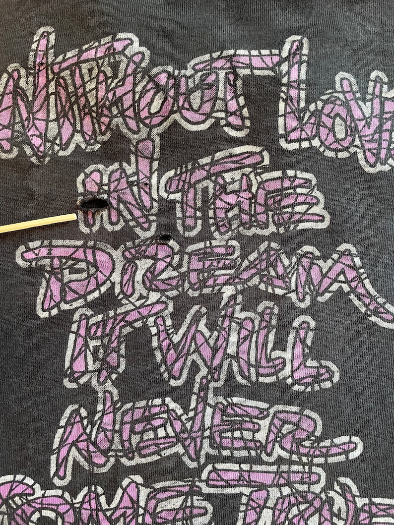 K&ouml;nnte beinhalten: Ein schwarzes T-Shirt mit einer lilafarbenen Grafik, auf der "Without love in the dream it will never come true" steht.