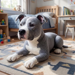 May include: A large, handmade crochet dog in a relaxed pose. The dog is primarily grey with white accents on its chest, paws, and face. It is lying on a patterned rug in a child's bedroom, creating a cosy and inviting atmosphere.