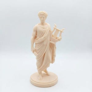 Peut inclure: Une figurine monochrome beige clair représentant un personnage debout vêtu d'une toge drapée et d'une couronne de laurier. Le personnage tient une petite lyre dans la main gauche et se tient sur une base circulaire, en matériau mat et uni.