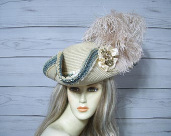 May include: A white and blue hat with a large, fluffy feather plume. The hat has a wide brim and is decorated with a white and gold flower.