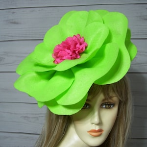 May include: A large, bright green felt flower with a pink felt center. The flower is worn as a hat.