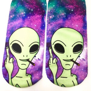May include: A pair of colorful socks with a galaxy print and a green alien with a cigarette in its mouth giving the middle finger.