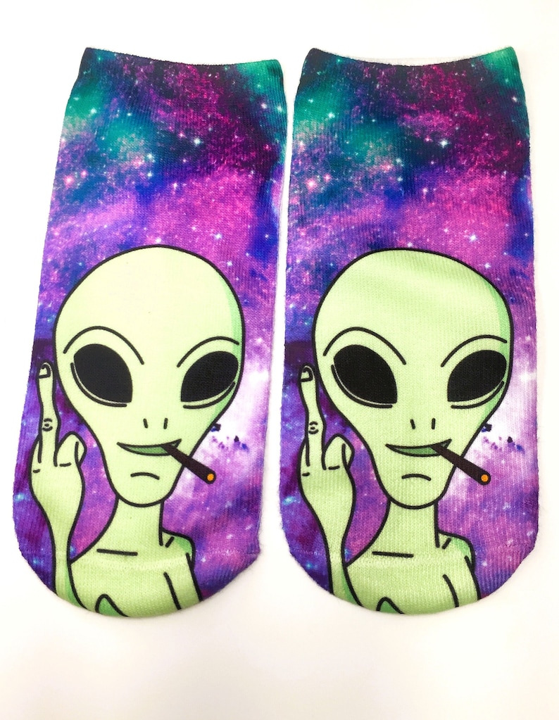 May include: A pair of colorful socks with a galaxy print and a green alien with a cigarette in its mouth giving the middle finger.
