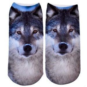 May include: A pair of grey and white ankle socks with a wolf face printed on them. The wolf has brown eyes and a black nose.