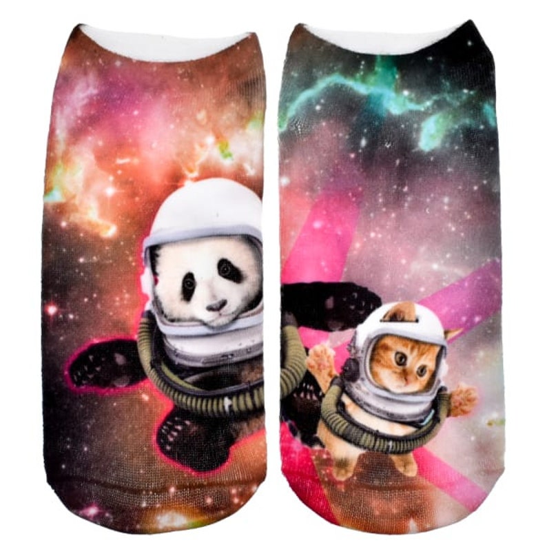 May include: A pair of colorful socks with a panda and a cat wearing astronaut suits floating in space. The socks have a galaxy print with stars and nebulae.