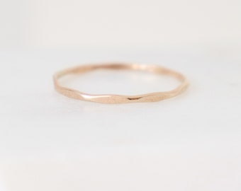 Pode incluir: Um anel de banda de ouro rosa fino e martelado.