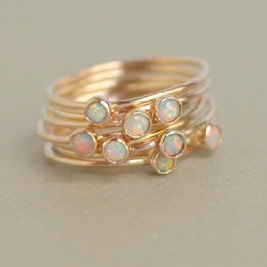 May include: A set of five gold rings with small opal stones. The rings are stacked on top of each other and the opals are arranged in a cluster.