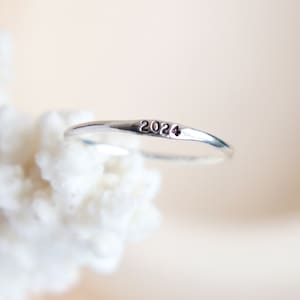 May include: A silver ring with the year 2024 engraved on it.