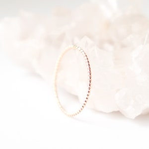May include: A delicate gold ring with a twisted, rope-like design. The ring is simple and elegant, perfect for everyday wear.