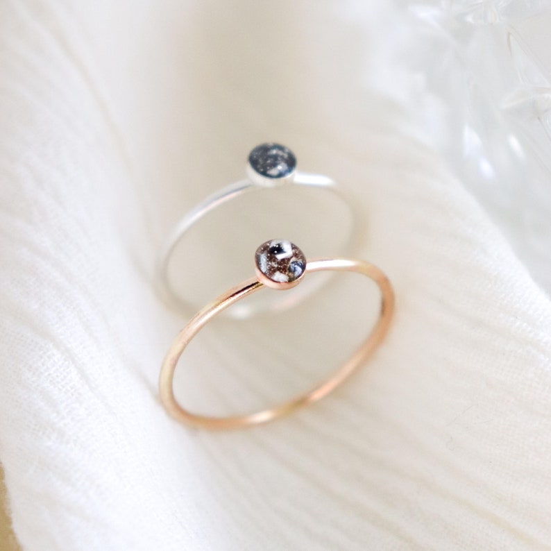 Memorial cremated ashes keepsake rings made from UV resin in sterling silver and solid 14k gold settings are showcased on a light textured background.