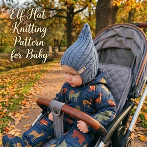 Peut inclure: Un bonnet d'elfe en tricot côtelé bleu avec un sommet pointu et une petite étiquette rectangulaire sur le côté. Le bonnet est porté par un bébé dans une combinaison bleu foncé à motif animalier, assis dans une poussette grise en automne.