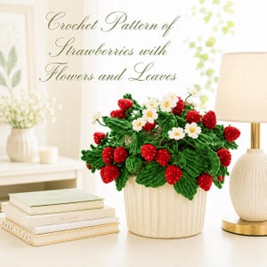Könnte beinhalten: Gehäkelte Erdbeeranordnung in einem weißen Topf, mit roten Erdbeeren, weißen Blüten und grünen Blättern. Der Text "Crochet Pattern of Strawberries with Flowers and Leaves" steht oben. Die Anordnung steht auf einem weißen Tisch.