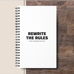 May include: A white spiral bound notebook with the text "Rewrite the rules" and the tagline "No limits, no boundaries, no excuses".