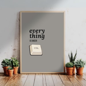 Puede incluir: Un póster enmarcado con un fondo gris y el texto "everything is under CTRL" en negro. La imagen incluye una tecla de computadora etiquetada como "CTRL". El póster se muestra sobre una superficie de madera con plantas en macetas.