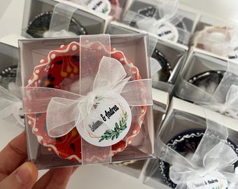 May include: A collection of small, colorful ceramic bowls with white trim, packaged in clear plastic boxes with white lids. Each box is tied with a white ribbon and a round tag with the text "Selin & Andrea".