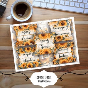 May include: A set of Bible tabs with a sunflower design. Each tab is labeled with a book of the Bible, such as Exodus, Genesis, and Deuteronomy. The tabs are arranged in a tray, with a coffee cup and keyboard in the background.