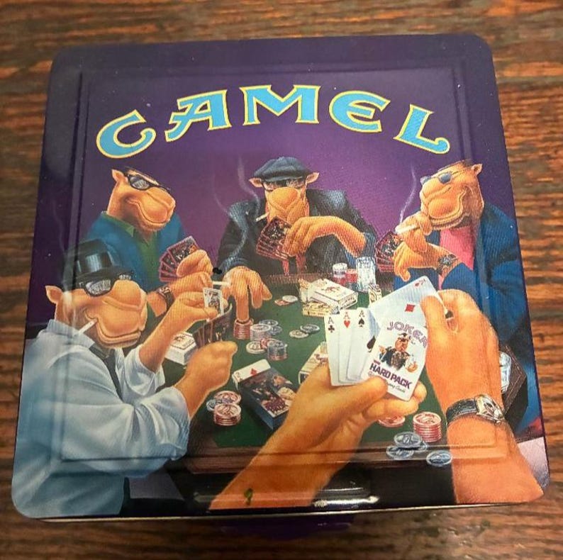 May include: A vintage Camel cigarette tin featuring a poker game scene with anthropomorphic camels. The tin has a purple background with the Camel logo in teal. The poker scene includes playing cards, chips, and cigarettes.