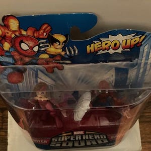 May include: Marvel Super Hero Squad action figures in a plastic package. The packaging features Iron Man, Spider-Man, and Wolverine. The package reads "HERO UP!" and "Marvel Super Hero Squad". The figures inside are visible.