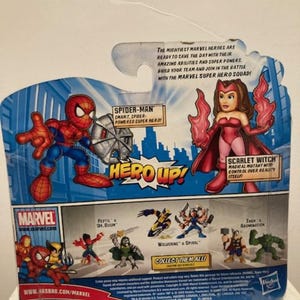 May include: Marvel Super Hero Squad action figure packaging featuring Spider-Man and Scarlet Witch. The packaging includes the text "HERO UP!" and "Collect Them All!" with additional Marvel characters.