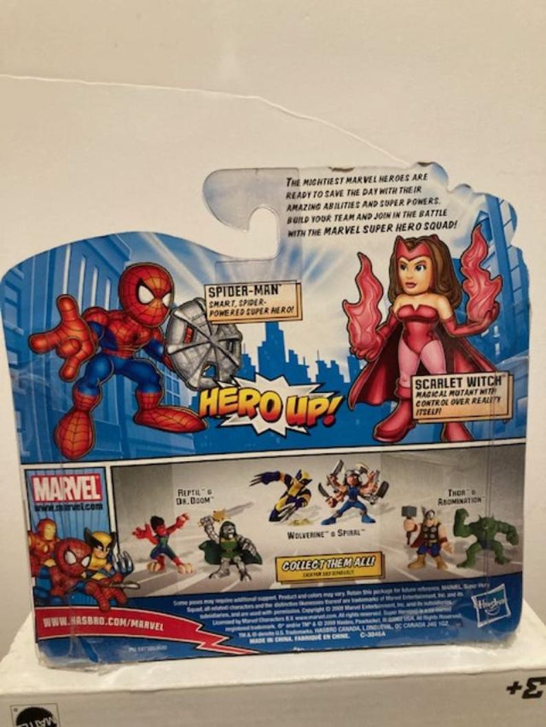 May include: Marvel Super Hero Squad action figure packaging featuring Spider-Man and Scarlet Witch. The packaging includes the text "HERO UP!" and "Collect Them All!" with additional Marvel characters.