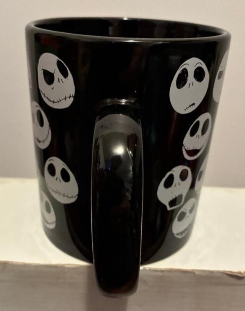 Puede incluir: Taza de cer&aacute;mica negra con caras blancas de Jack Skellington. La taza tiene un asa negra y un acabado brillante. El dise&ntilde;o se repite alrededor de la taza, creando una est&eacute;tica espeluznante y divertida.