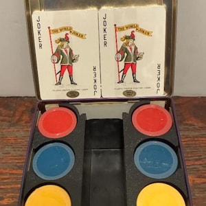 May include: A vintage card game set in a metal tin. The set includes two "Joker" playing cards and colorful poker chips in red, blue, and yellow. The tin is purple with a silver lid.