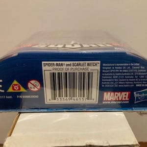 May include: A blue and red action figure package featuring the text "SPIDER-MAN and SCARLET WITCH". The package includes a barcode, the Marvel logo, and the Hasbro logo. The age range is 0-3.