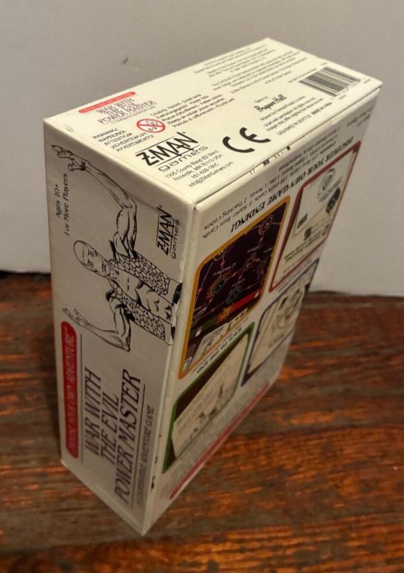 K&ouml;nnte beinhalten: Eine Brettspielbox mit dem Titel "War With The Evil Power Master" von Z-Man Games. Die Box ist wei&szlig; mit rotem und schwarzem Text und Illustrationen. Das Spiel ist f&uuml;r Spieler ab 10 Jahren und f&uuml;r mehr Spieler.