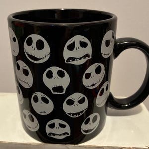 Puede incluir: Taza de cer&aacute;mica negra con m&uacute;ltiples caras blancas de Jack Skellington con diversas expresiones. La taza tiene un asa negra y es adecuada para bebidas fr&iacute;as o calientes. Un gran regalo para los fans de la pel&iacute;cula.