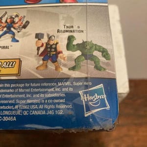 May include: A Marvel Super Hero action figure package featuring Thor and Abomination. The package includes the Hasbro logo and text that reads "SCARLET WITCH MAGICAL MUTANT WITH CONTROL OVER REALITY ITSELF!"