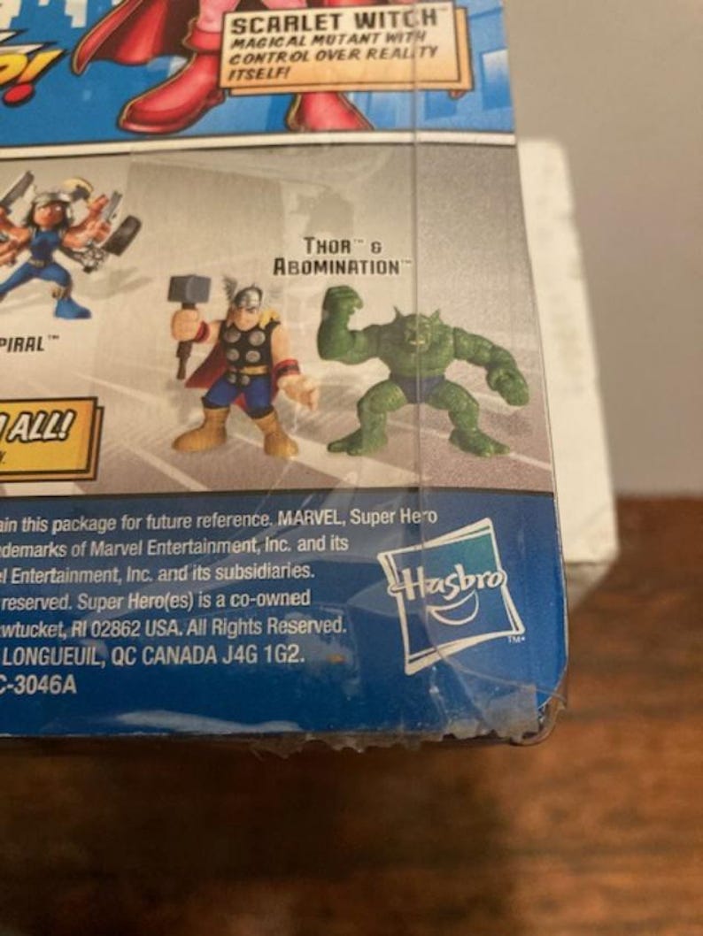 May include: A Marvel Super Hero action figure package featuring Thor and Abomination. The package includes the Hasbro logo and text that reads "SCARLET WITCH MAGICAL MUTANT WITH CONTROL OVER REALITY ITSELF!"