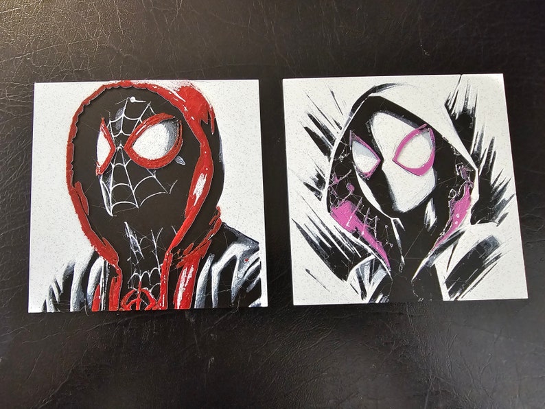May include: Two black and white illustrations of masked figures wearing red and pink hooded sweatshirts. The figures are drawn in a stylised, graphic style.