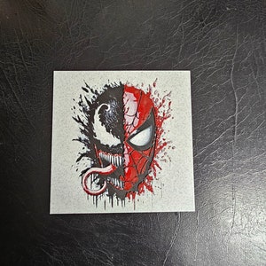 May include: A black and red graphic illustration of Spider-Man and Venom's faces, with a white background and black and red splatters.