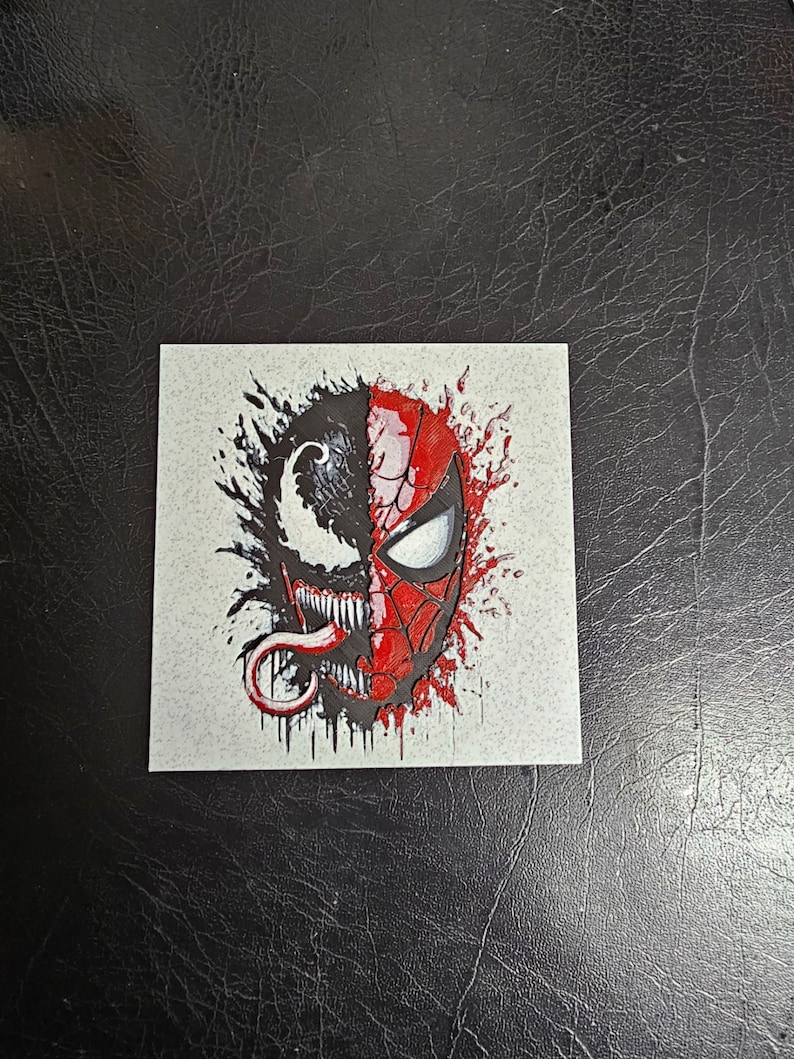 May include: A black and red graphic illustration of Spider-Man and Venom's faces, with a white background and black and red splatters.