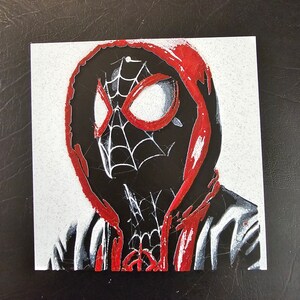 May include: An illustration of Spider-Man wearing a red hooded sweatshirt. The illustration is done in a stylised, almost pixelated style.