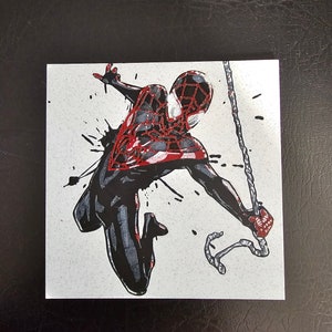 May include: A black and red stylised illustration of Spider-Man swinging through the air with a web line. The background is white with black splatters of paint.