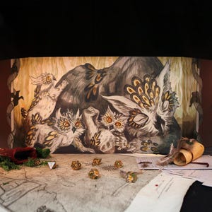 May include: A multi-panel game screen with an owl family illustration in grey, brown, and gold. Dice, a red pouch, and a scroll are on a map-like surface, suggesting a tabletop role-playing game setting.
