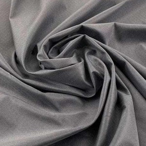 Può includere: Primo piano di un tessuto grigio scuro con una texture sottile. Il tessuto è piegato e drappeggiato, mostrando il suo aspetto liscio e morbido.