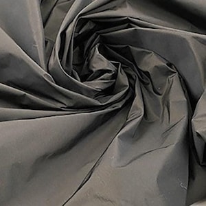 Könnte beinhalten: Nahaufnahme eines dunkelgrauen Stoffes mit glatter, seidenartiger Textur. Der Stoff ist gefaltet und drapiert und erzeugt einen weichen, fließenden Look.